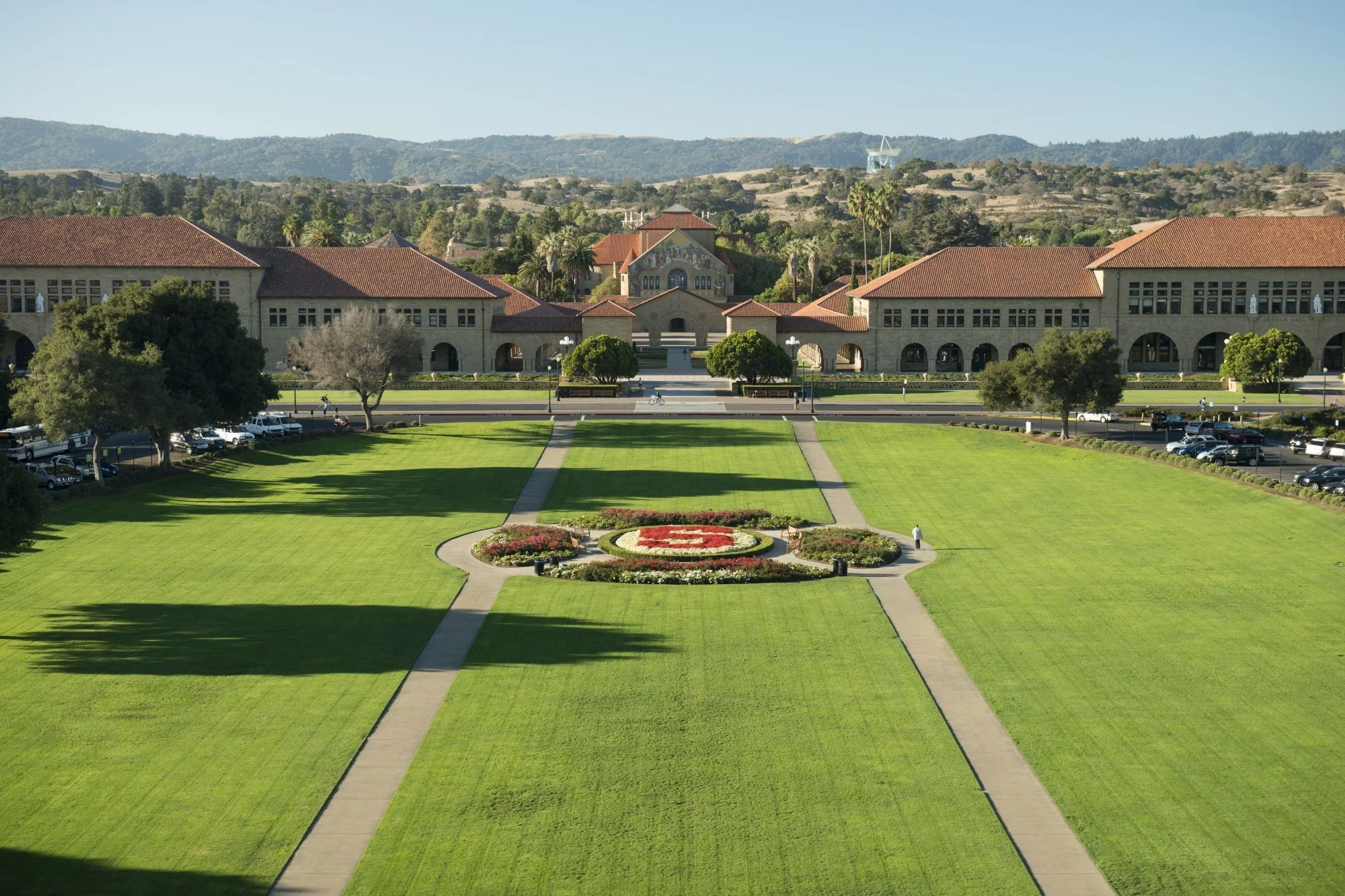 a photo of Stanford University's campus lawn. stone buildings with amber red terracotta roofs